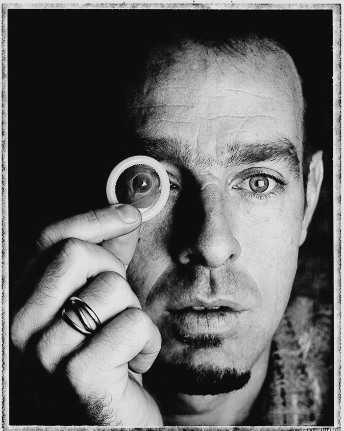 Portrait d'un homme tenant une loupe devant son œil